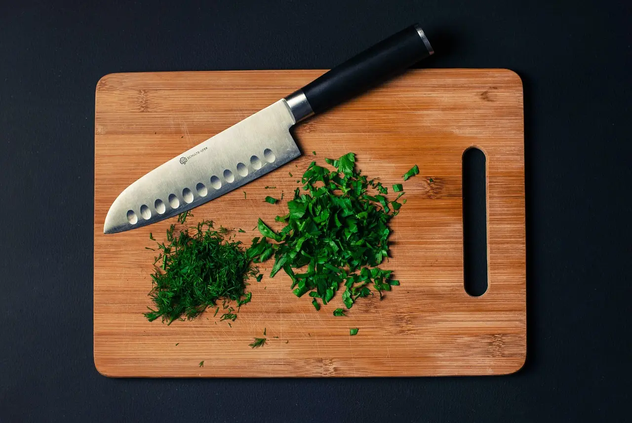 Eneldo fresco picado sobre una tabla de cortar de madera, listo para usar en la cocina